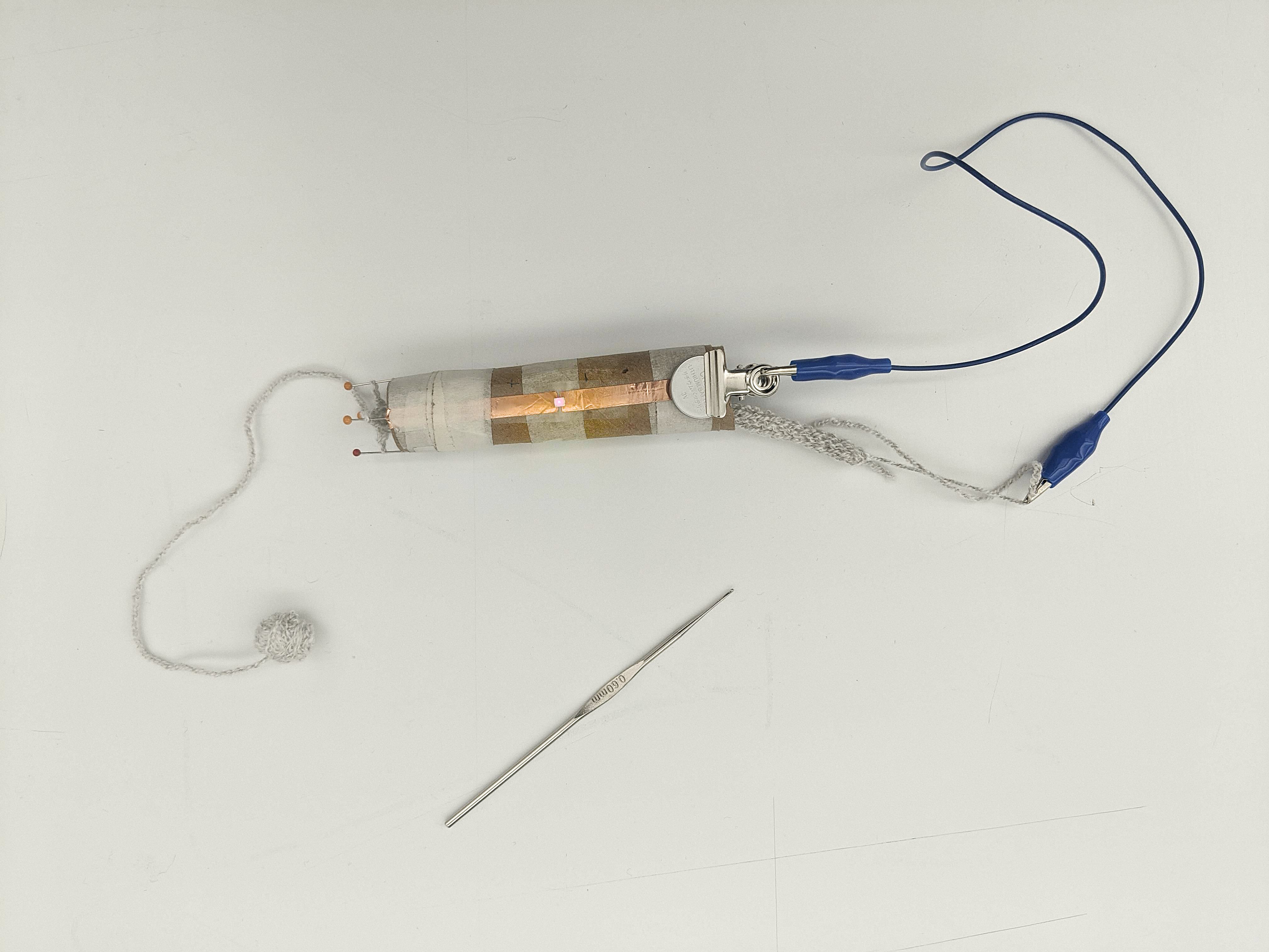 process picture of knitting conductive yarn, connected in a circuit with an led on the knitting nancy lit up